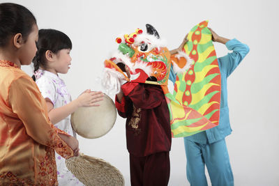 Side view of smiling girls with friends wearing costume against white background