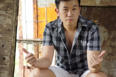 Portrait of man showing thumbs ups while sitting in abandoned room