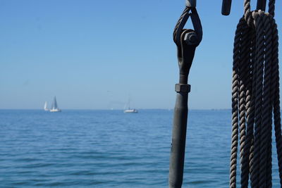 Sailboat in sea against clear blue sky