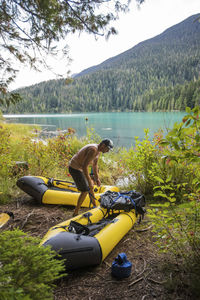 Man on lakeshore, preparing his boats for a packrafting trip at lake.