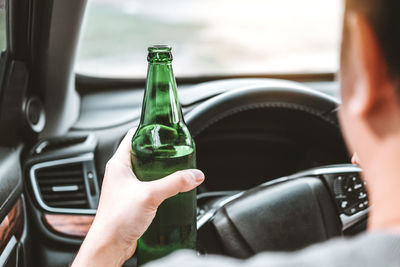 Midsection of man holding glass in car