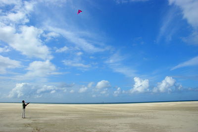 Man standing on sand dune in desert against sky