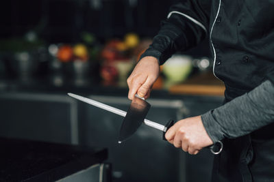 Midsection of chef sharpening knife