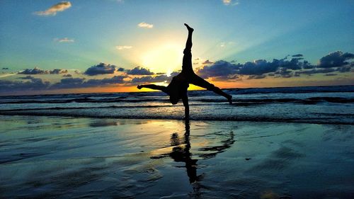 Silhouette woman on beach against sky during sunset