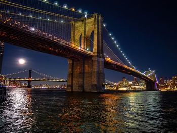 Illuminated bridge over river at night