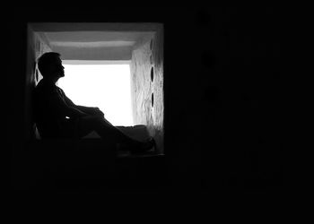 Woman sitting on window at home