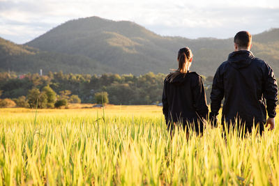 Rear view of couple standing at farm against mountains