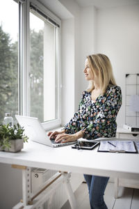 Smiling businesswoman looking out of window while sitting at office