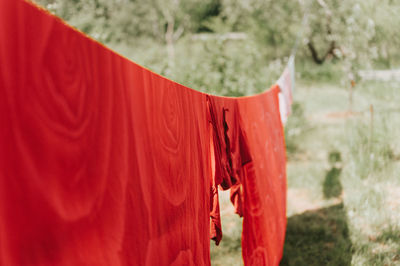 Red bed linen is dried on clothesline on the street in courtyard of village household cottage house