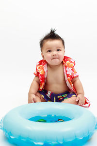 Cute baby boy with inflatable ring against white background