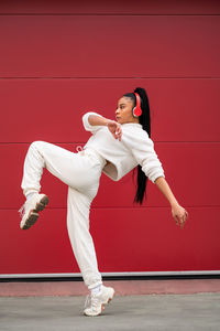 Portrait of a young african american woman dancing on a red colored background