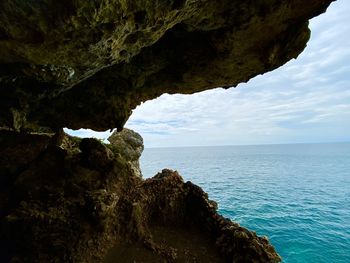 Rock formation by sea against sky