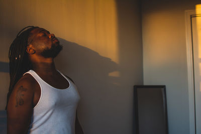 Young man standing against wall at home