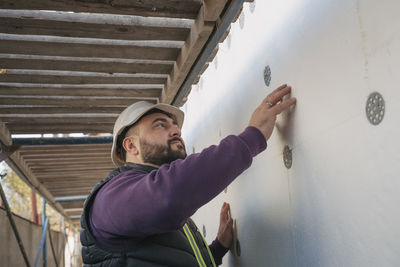 Construction worker examining polystyrene foam wall on site