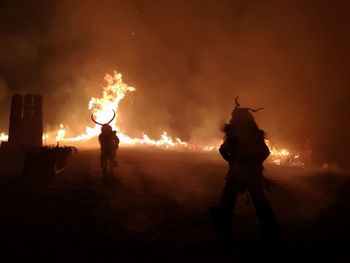 Silhouette men walking against fire at night