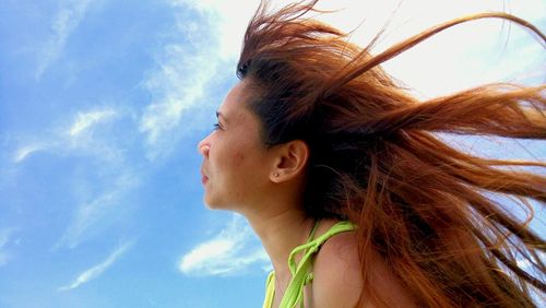 Low angle view of woman with long hair against sky