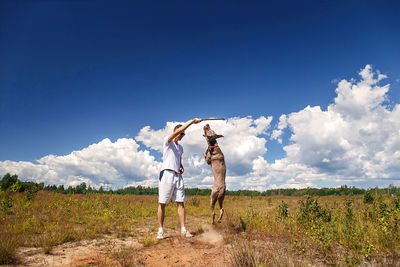 Rear view of woman standing on field against sky