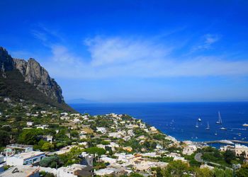 Scenic view of sea and cityscape against blue sky