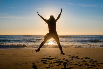 Rear view of woman jumping on beach