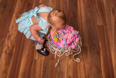 High angle view of cute girl eating cake  on hardwood floor