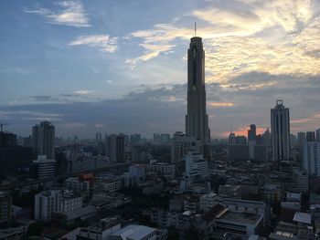 Modern buildings in city against sky during sunset