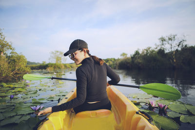 Side view of man sitting on boat in lake