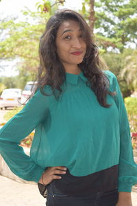 Portrait of smiling young woman standing against wall