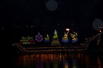 Illuminated firework display over lake against sky at night