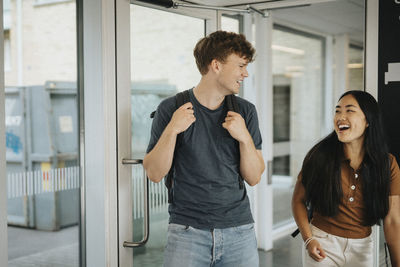 Cheerful male and female students entering classroom in university