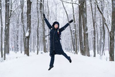 Woman jumping on snow covered forest