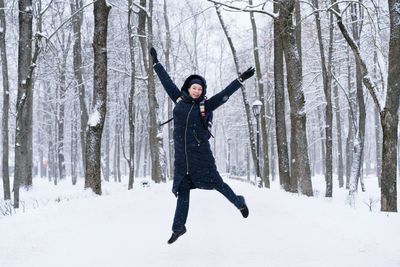 Man jumping on snow covered forest