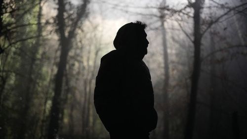 Silhouette woman standing in forest during sunset