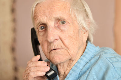 Close-up of a 90-year-old elderly retired woman who is talking smiling on the phone. selective focus