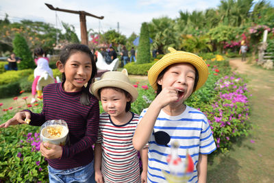 Portrait of siblings eating popcorns while standing on field