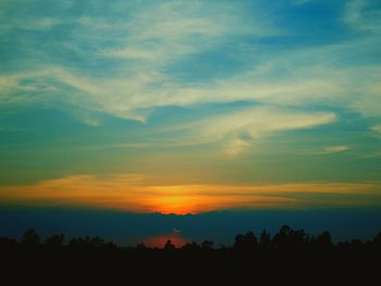 Silhouette trees against dramatic sky during sunset