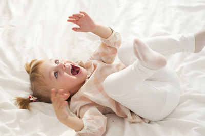 High angle view of girl playing on bed at home