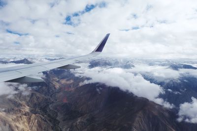 Airplane flying over mountains against sky
