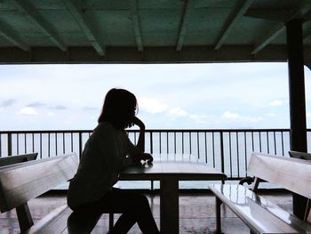 Silhouette woman sitting at table against sky