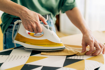 Close-up of an unrecognizable woman ironing clothes on an ironing board.