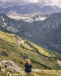 Rear view of woman sitting on mountain