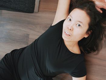 High angle portrait of young woman lying on sofa at home