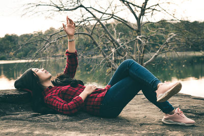Young woman lying down while sitting on tree