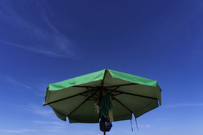 Low angle view of umbrella against blue sky