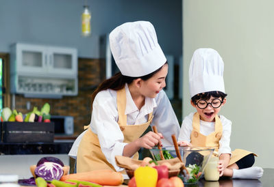 Mother with cute son preparing food in kitchen at home