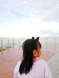 Rear view of woman looking at camera against sky