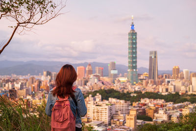 Rear view of woman standing against buildings in city