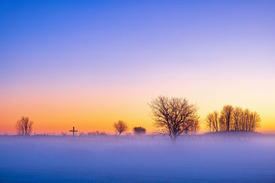 Winter sunrise with fog and a religious cross in silhouette