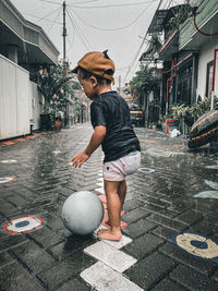 Full length of man holding ball while standing on street