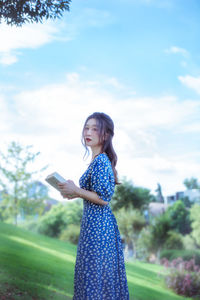 Portrait of young woman standing against sky