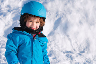 Portrait of smiling boy standing on snow covered land